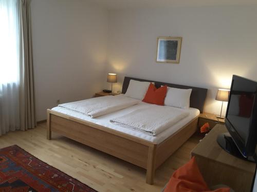 a bedroom with a bed with two pillows and a television at B&B Elfi in Salzburg