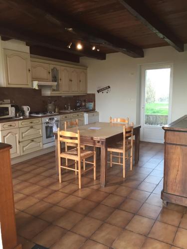 eine Küche mit einem Holztisch und Stühlen sowie einem Fenster in der Unterkunft La Maison de Gaston in Saint-Cirgue