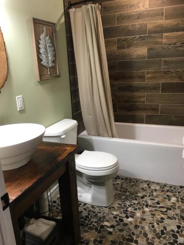 a bathroom with a toilet and a tub and a sink at The Village Suites in Wellington