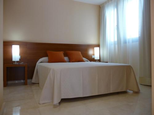 a bedroom with a large bed with two orange pillows at Hotel Verti in Corró de Vall