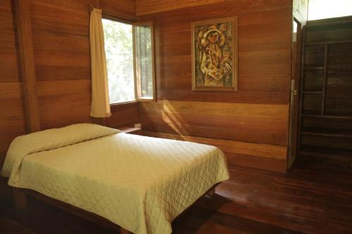 1 dormitorio con 1 cama en una habitación con paredes de madera en La Musa Verde, en Tarapoto