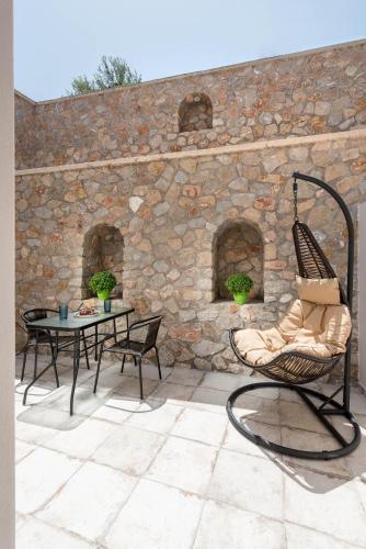 a patio with a chair and a table and a stone wall at Elia Residences Santorini in Karterados