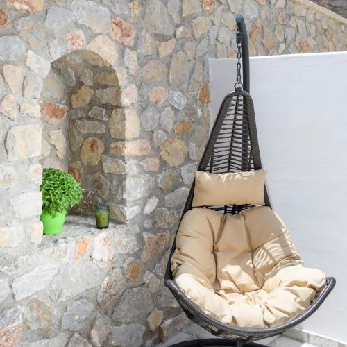 a chair in front of a stone wall at Elia Residences Santorini in Karterados