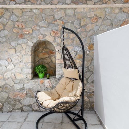 a wicker chair sitting in front of a stone wall at Elia Residences Santorini in Karterados