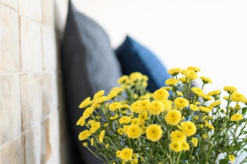a vase filled with yellow flowers next to a wall at Elia Residences Santorini in Karterados