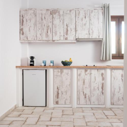 a kitchen with white wooden cabinets and a counter top at Elia Residences Santorini in Karterados
