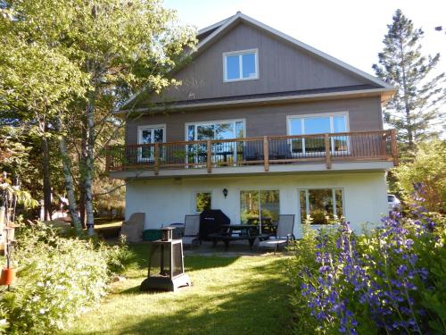 a large house with a deck on a yard at Chalets Laurentides Mont-Tremblant in Mont-Tremblant
