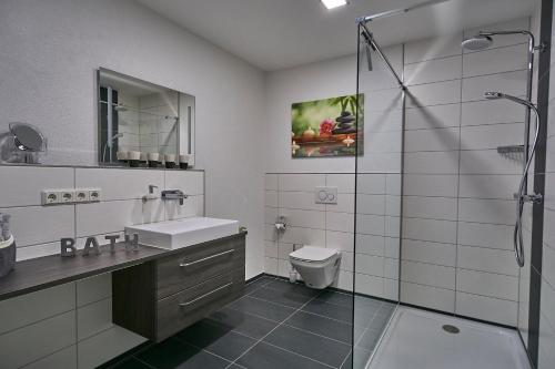 La salle de bains est pourvue d'un lavabo, de toilettes et d'une douche. dans l'établissement Ferienwohnung Atrium, à Niederlinxweiler