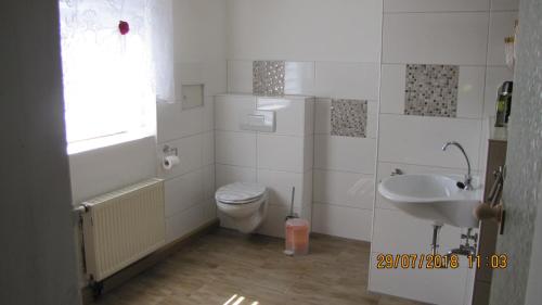 biała łazienka z toaletą i umywalką w obiekcie Ferienzimmer Haus Läsker w mieście Mittelndorf