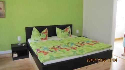 uma cama com um edredão verde e almofadas em Ferienzimmer Haus Läsker em Mittelndorf