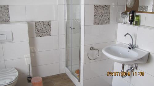 a white bathroom with a sink and a toilet at Ferienzimmer Haus Läsker in Mittelndorf