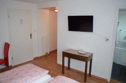 Zimmer mit einem Tisch und einem TV an der Wand in der Unterkunft Hotel Schiff in Horn