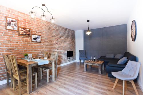 a living room with a table and a brick wall at Apartament Starówka 3 in Toruń