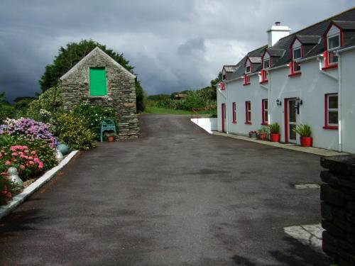 a road leading to a white building with red windows at Reenmore Farmhouse in Ahakista