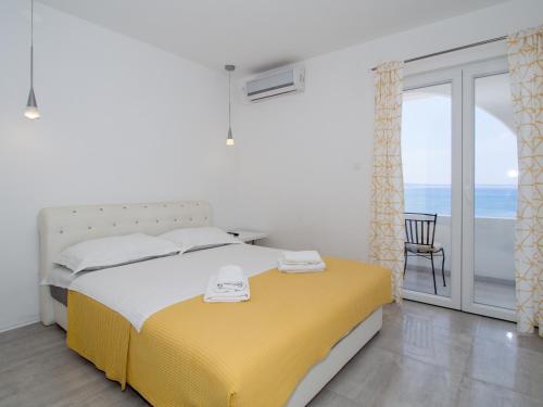 a bedroom with a yellow and white bed and a balcony at Villa Tamaris on the beach in Podstrana