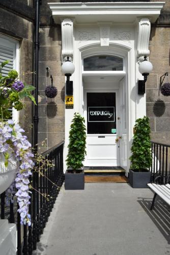 a white door with two potted plants on a building at Edinburgh37 in Edinburgh