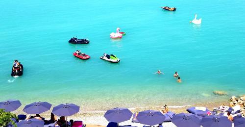 people on a beach with umbrellas and boats in the water at Marzi Boutique Hotel in Nerátza