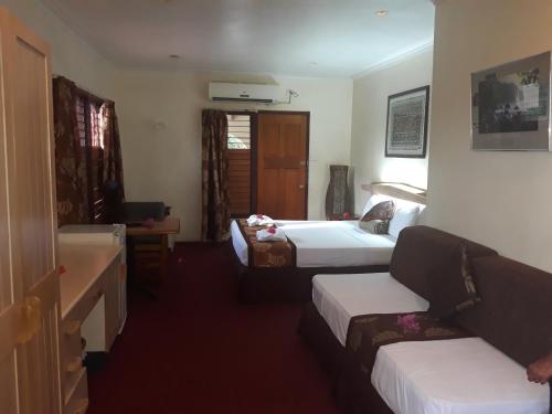a hotel room with two beds and a couch at Grand Eastern Hotel in Labasa