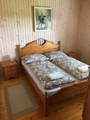 a wooden bed in a room with a wooden floor at Mézesfészer apartman in Cserkút
