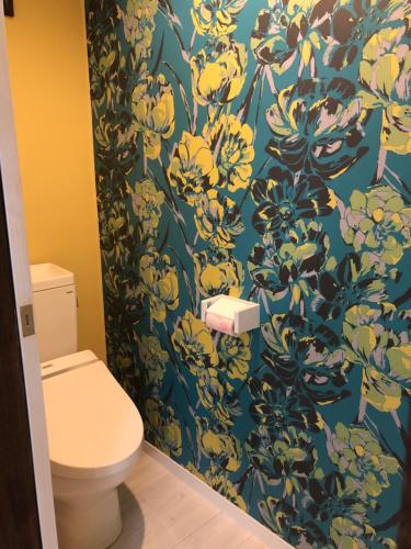 a bathroom with a toilet and a blue and yellow wallpaper at Amami Weekly House Nico nico in Amami