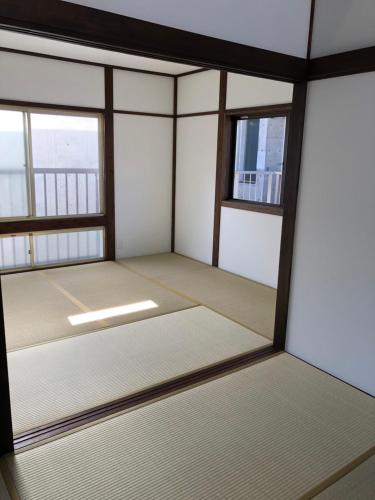 an empty room with two windows in a building at Amami Weekly House Nico nico in Amami