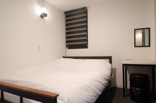 a bedroom with a white bed and a desk at One Way Guesthouse Busan in Busan