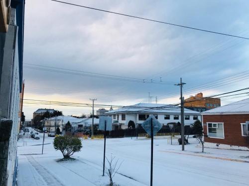 una calle cubierta de nieve con casas y una señal de stop en Hostal Chalet Las Violetas, en Punta Arenas