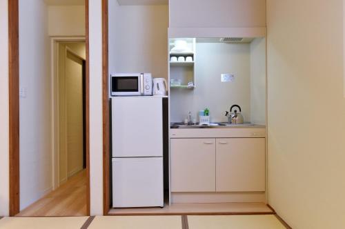 a small kitchen with a refrigerator and a microwave at Hinata-an in Yufu