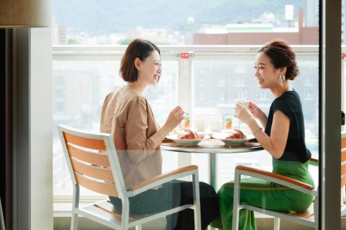 two women sitting at a table eating food at Hakodate Danshaku Club Hotel & Resorts in Hakodate