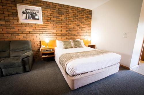 a bedroom with a bed and a brick wall at Sportslander Motor Inn in Moama