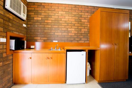 a kitchen with wooden cabinets and a sink at Sportslander Motor Inn in Moama