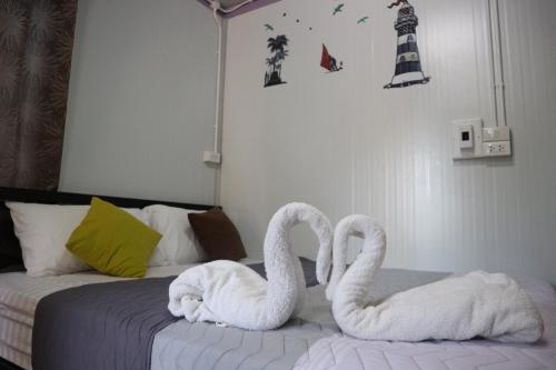 two white swans sitting on top of a bed at Baan Suchanuch in Don Sak
