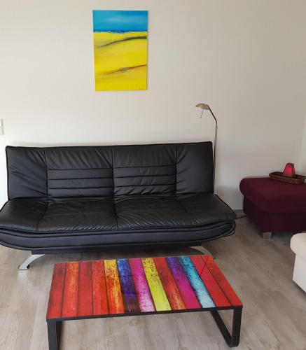 a black couch in a living room with a colorful rug at Marina View in Bad Zwischenahn