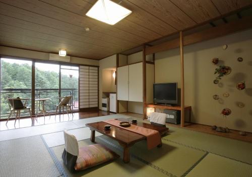 a large living room with a table and a tv at Hishino Onsen Tokiwakan in Komoro