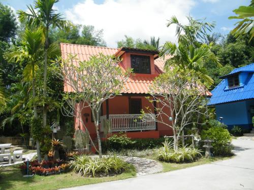 a house with a red roof and palm trees at Ya Teng Homestay in Ban Tha Sai