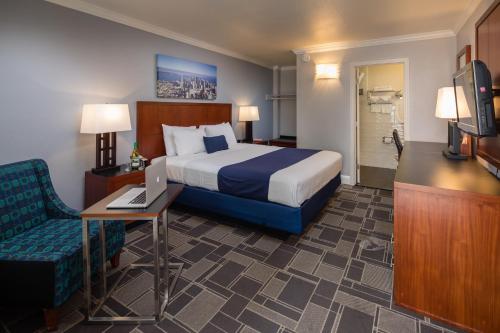 サンフランシスコにあるベイ ブリッジ イン サンフランシスコのベッド、デスク、テレビが備わるホテルルームです。