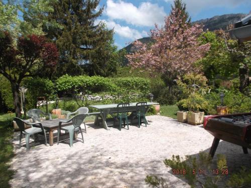 a patio with a table and chairs and trees at 965 avenue leopold Fabre GITE LE LANTIER in Lans-en-Vercors