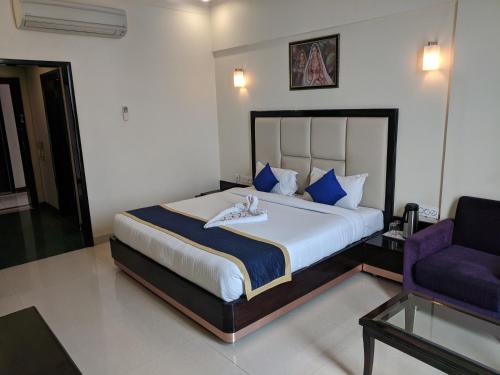 a bedroom with a large bed and a purple chair at Chandra Imperial in Jodhpur