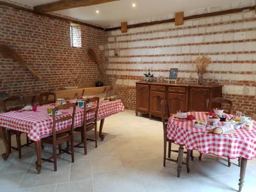 une salle à manger avec deux tables avec une nappe rouge et blanche dans l'établissement La Tilia, à Saint-Riquier