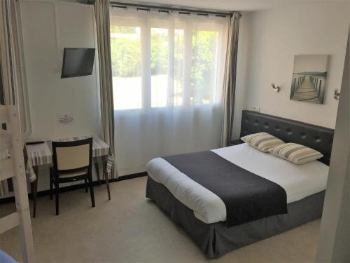 1 dormitorio con cama, mesa y ventana en Auberge Les Mufliers - Hôtel Les Forges, en Pontenx-les-Forges