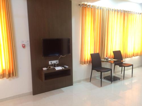 a room with a table with chairs and a television at Hotel Shiva's Inn in Trimbak