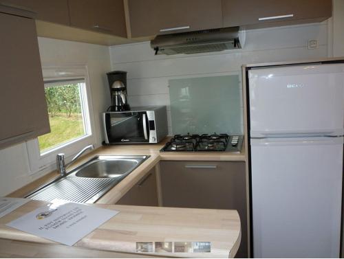 a kitchen with a stove, refrigerator, sink and dishwasher at Eté indien-hôtellerie de plein air in Wimereux