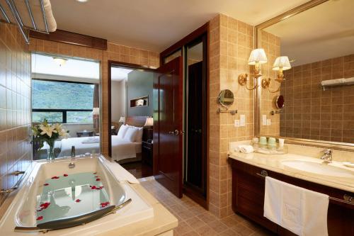 a bathroom with a tub and a sink and a bedroom at C&D Resort,Wuyi Mountain in Wuyishan