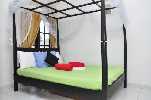 a bedroom with a black and green canopy bed with colorful pillows at Bon Accord Mirissa in Mirissa