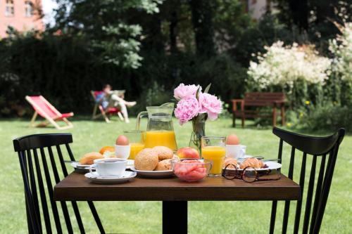 uma mesa com alimentos de pequeno almoço, sumo e flores em Zulian Aparthotel by Artery Hotels em Cracóvia