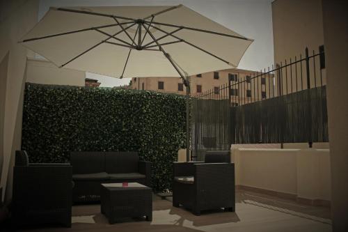 a patio with an umbrella and chairs and a hedge at Real Rooms in La Spezia