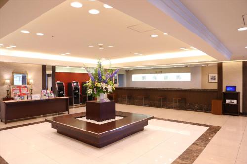 a lobby with a waiting area with flowers on a table at Hotel Hokke Club Hiroshima in Hiroshima