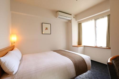 a hotel room with a bed and a window at Hotel Hokke Club Hiroshima in Hiroshima