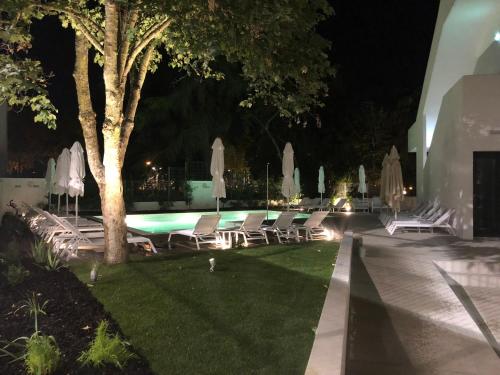 a group of lawn chairs and umbrellas at night at Evora Olive Hotel in Évora