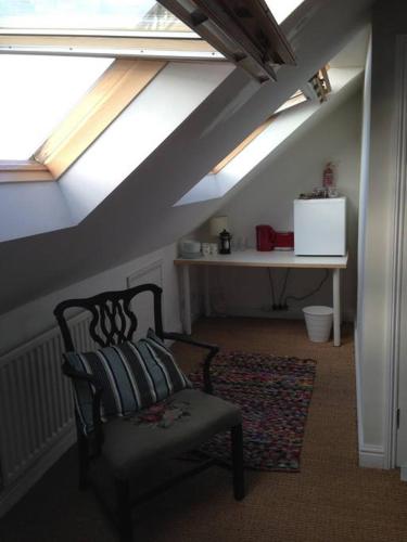 a attic room with a chair and a window at Fishponds Retreat Homestay in Bristol